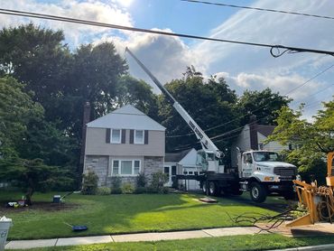 Professional crane service removing trees near a residential home by All Seasons Tree Services.