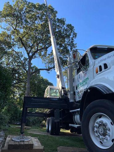 "Crane lifting a large log for safe removal near a home by All Seasons Tree Services in NJ.