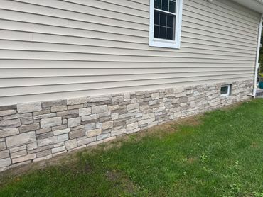 House exterior with beige siding and stone veneer lower wall near green lawn.