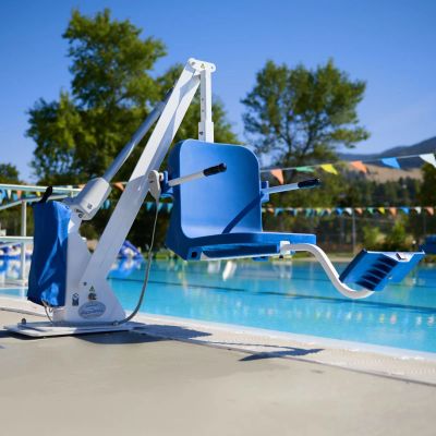 A blue, bolt-mounted pool lift attached to the side of an outdoor in-ground swimming pool