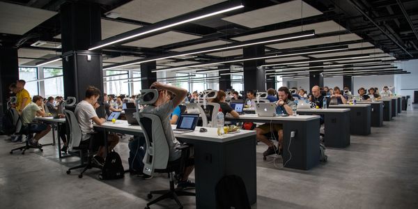 large open plan office with people sitting at desks with laptops in front of them