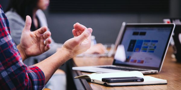 office meeting with man in front of laptop gesturing with his hands