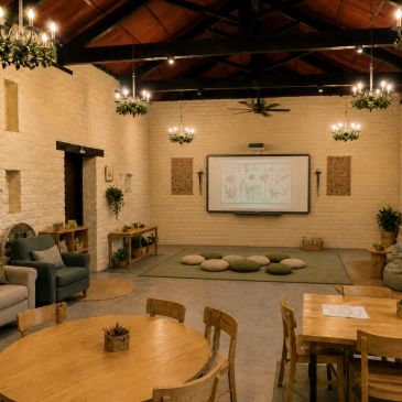Cozy classroom with round tables, cushions, and chandeliers under a wooden ceiling.