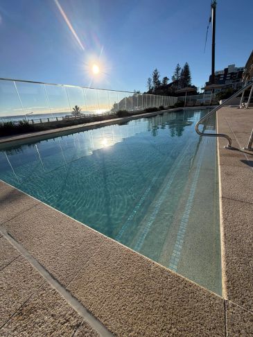 Outdoor pool beside the ocean at sunset.