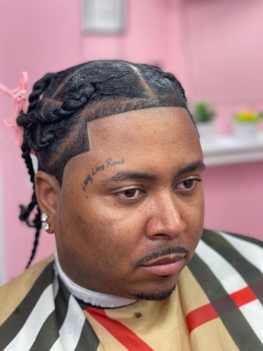 Man with braided hair and a fresh haircut in a barber's chair.