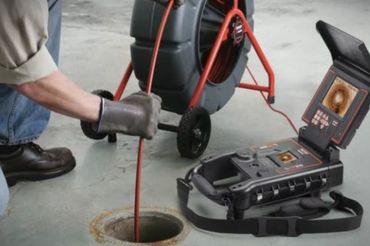 Person using a sewer inspection camera to check a drain.