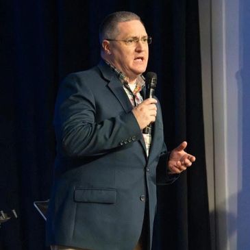 Adam Myrick delivering remarks from the stage of a public relations conference