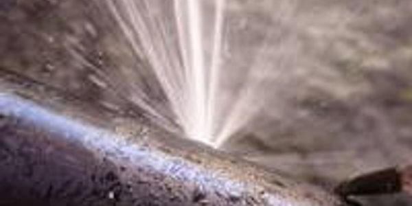 High-pressure water jet cutting through surface.