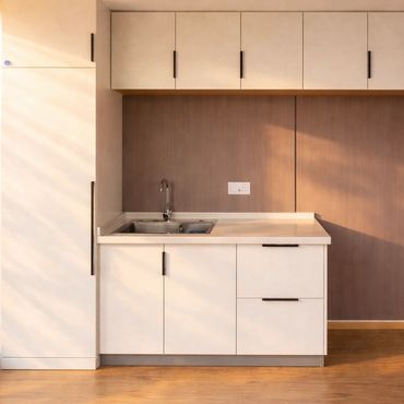 Minimalist kitchen with white cabinets, wood accents, and natural sunlight.