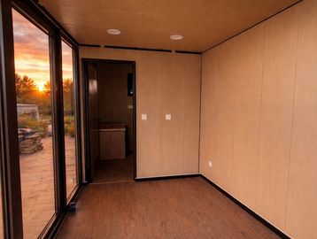 Empty room with large glass doors and wooden walls at sunset.