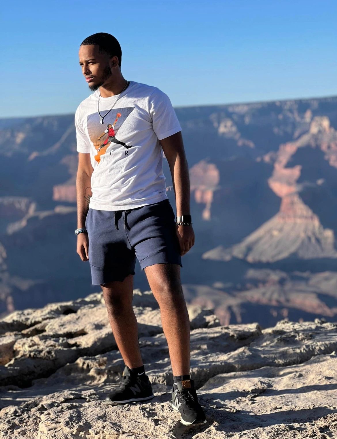 Man standing on rocky terrain with scenic canyon background.