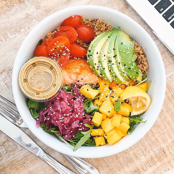 Colorful poke bowl with avocado, mango, salmon, tomatoes, and quinoa.