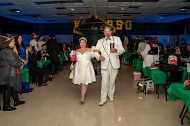 Newlyweds walking down the aisle in a decorated hall with guests.