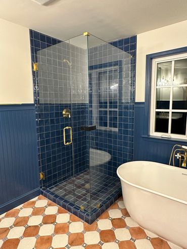 Modern bathroom with blue tiled shower and freestanding tub.