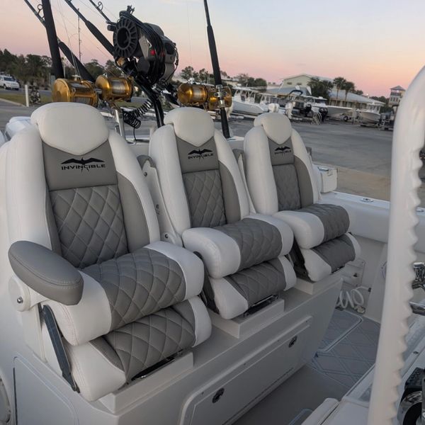 Three luxurious boat seats with fishing rods in the background at sunset.