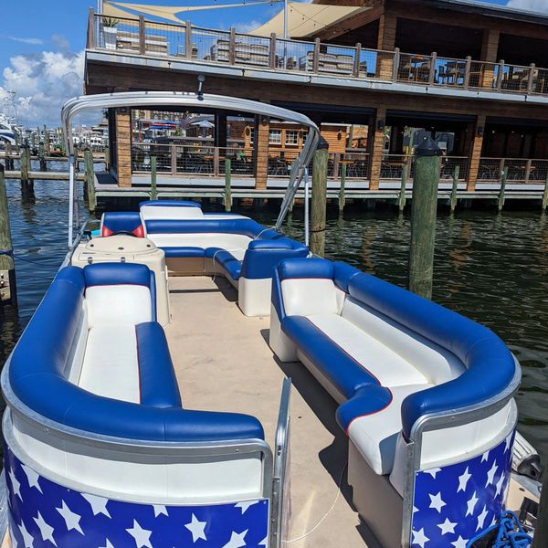 A pontoon boat with blue and white star-patterned sides docked at a marina.