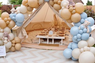 Elegant neutral and pastel blue outdoor bell tent picnic setup featuring a rustic table and balloons
