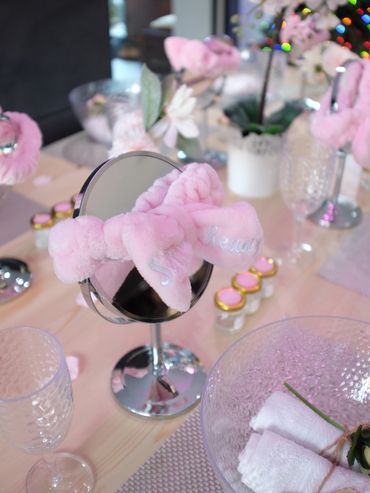 Spa party table with mirrors, pink headbands, and flowers.