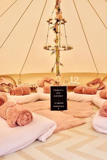 Luxe bell tent interior with rolled blankets and pink decor in Derby.