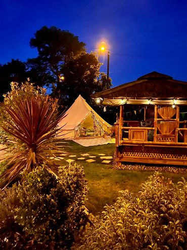 Evening bell tent setup with garden gazebo and warm lighting.