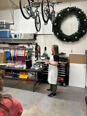 Woman in apron serving drinks in a decorated garage space.