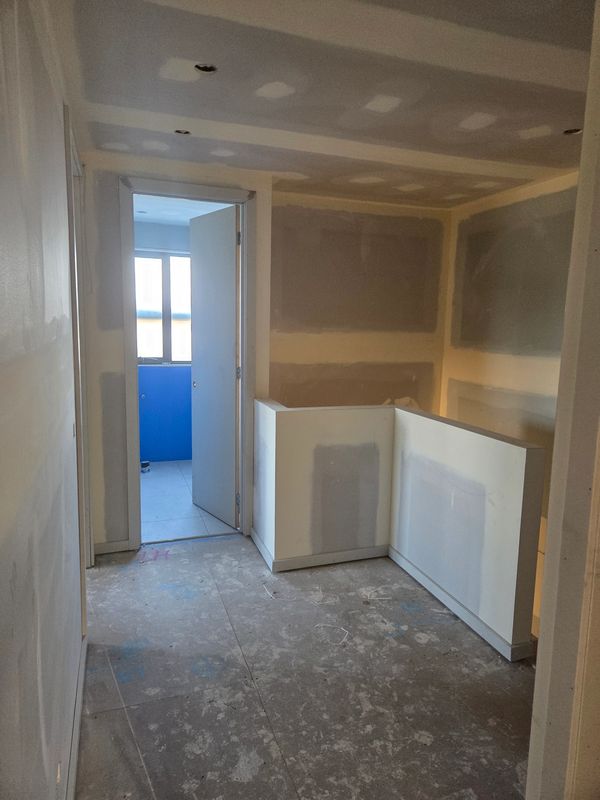 Unfinished interior hallway with drywall and open door to a blue room.