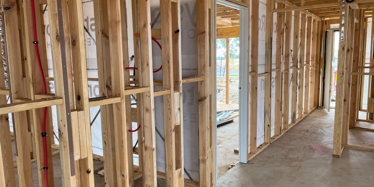 Framing and initial plumbing inside a house under construction.