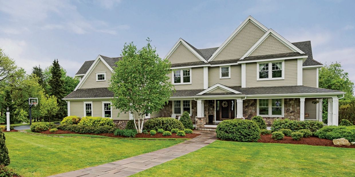 Spacious modern house with a large front yard and manicured landscaping.