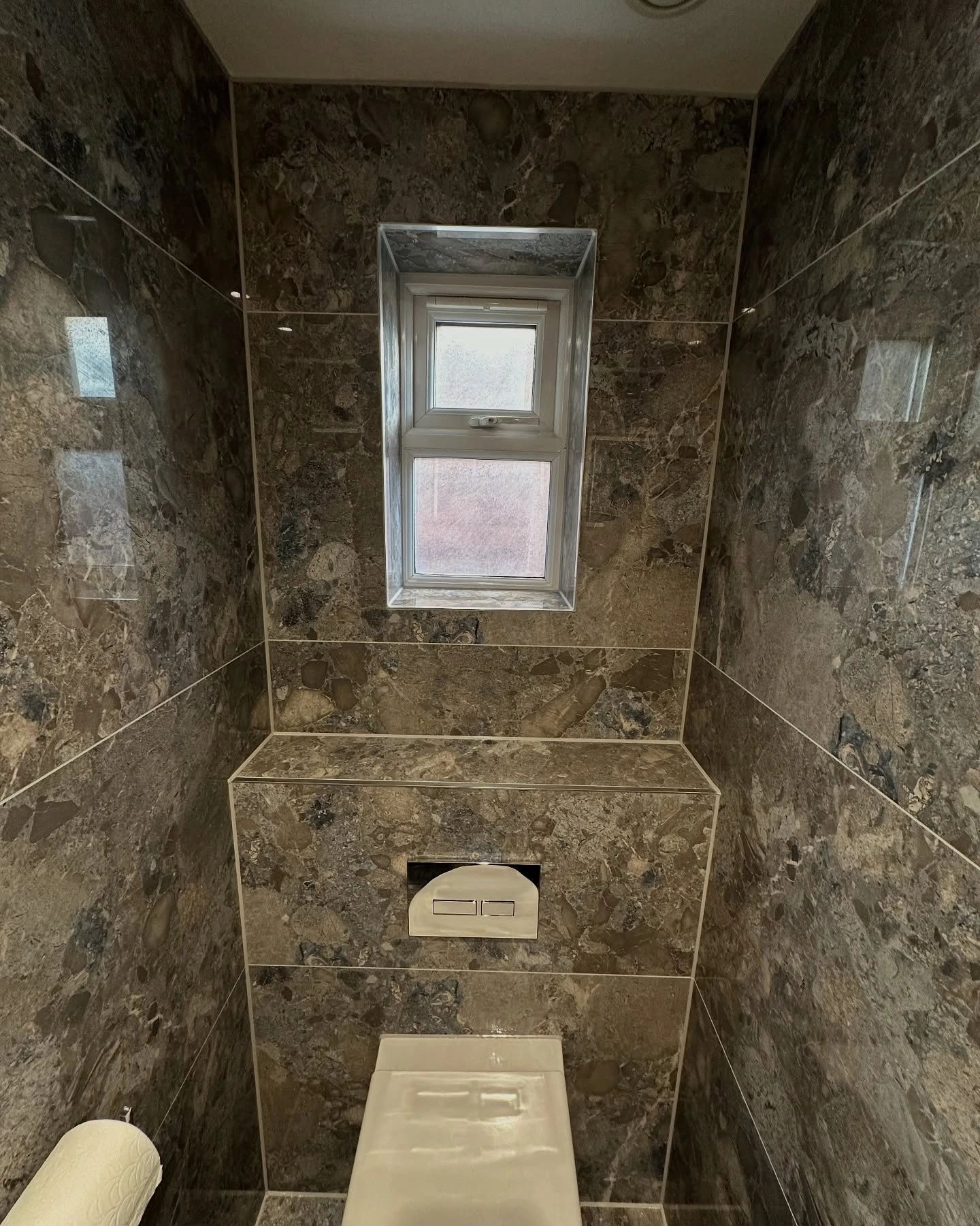 Small bathroom with a window and stone-textured walls.