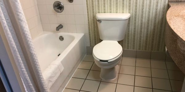 Hotel Remodeling before picture of a bathroom with old tile and built in vanity curved countertop