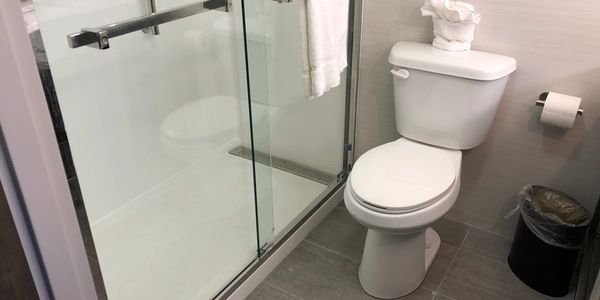 Hotel remodeling picture of a bathroom after a remodel showing new tile floor and bath to shower
