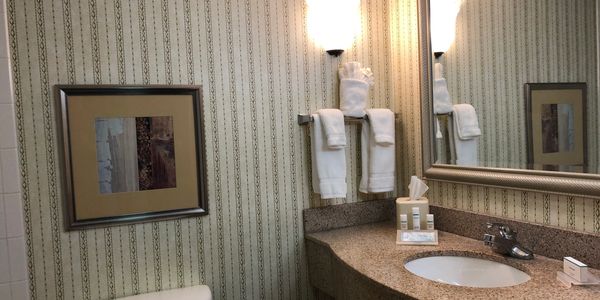 Hotel remodeling picture of a bathroom vanity before old wallpaper and sink is removed.