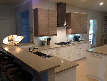 Modern kitchen with bar top and unique lamp. Under cabinet lights and glass backsplash  in Austin TX