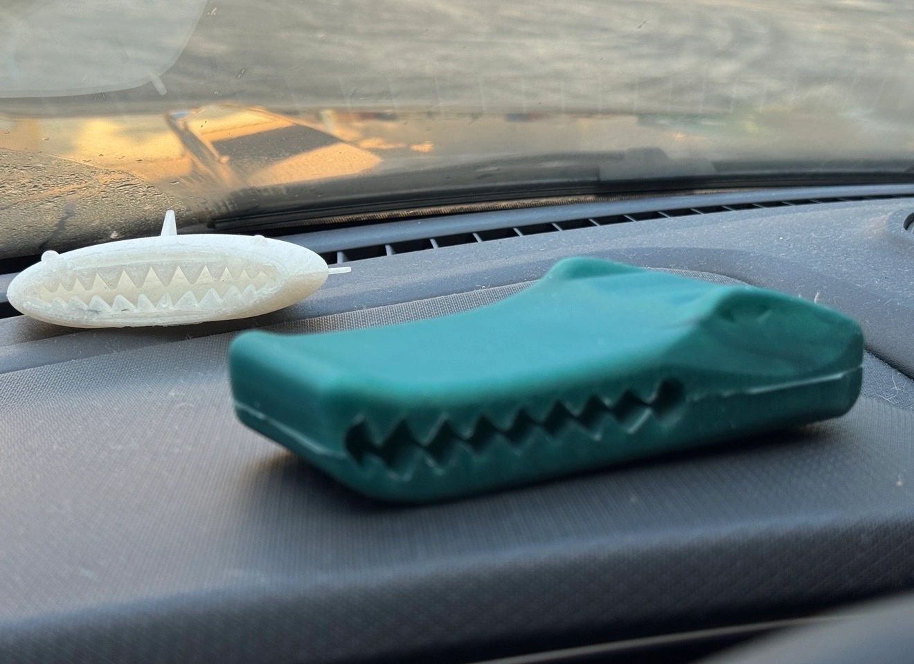 Two shark-shaped objects on a car dashboard.