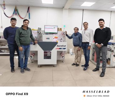 Five men standing around an AuraCut A6 machine in a workshop.