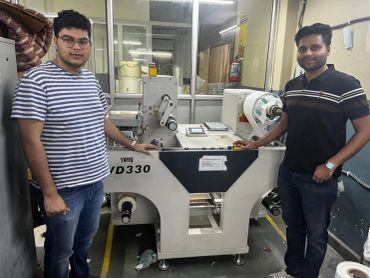 Two men standing beside a large industrial machine in a workshop.