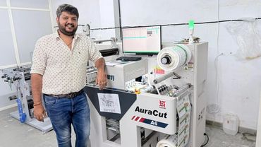 Man standing next to an AuraCut A6 cutting machine in a workspace.