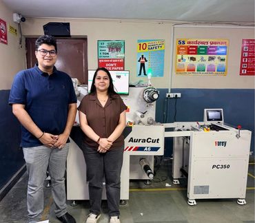 Two people standing in front of an AuraCut A6 industrial machine.
