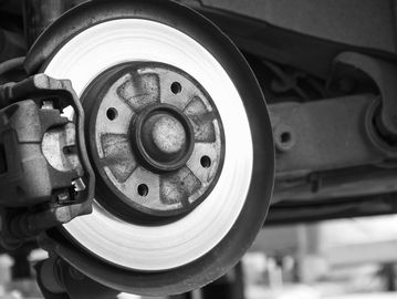 Close-up of a car brake disc and caliper in black and white.