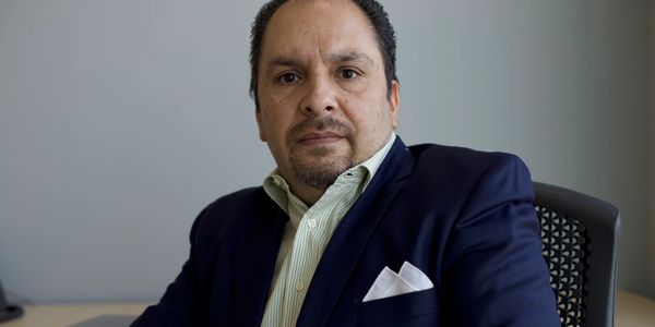 A man in a suit sitting and looking at the camera.