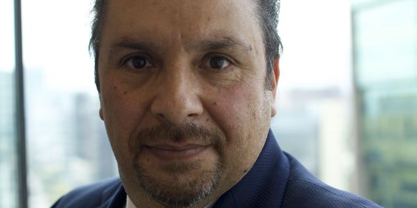 Man with dark hair and goatee in a suit jacket.