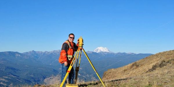 Surveyor working in a mountainous area with clear skies.