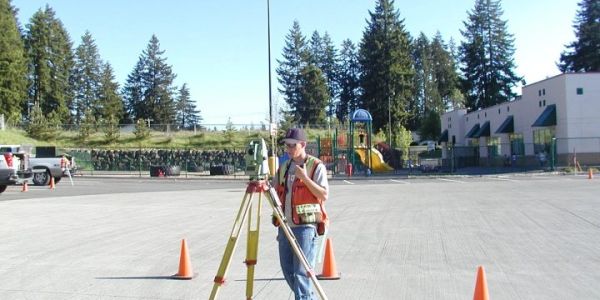 Surveyor working outdoors with equipment.