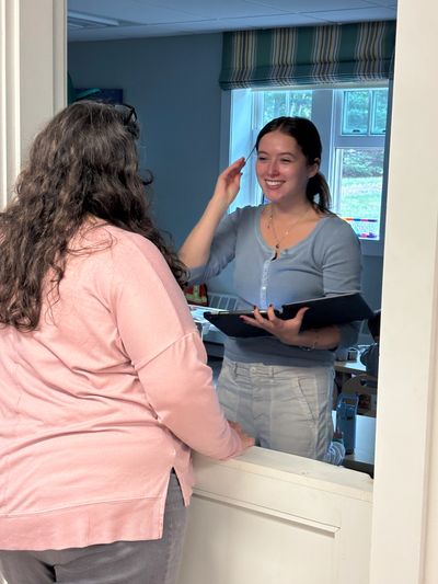 Two women conversing over a service counter indoors.