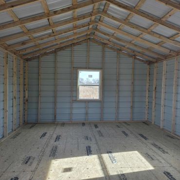 Interior of an unfinished wooden and metal shed with a window.