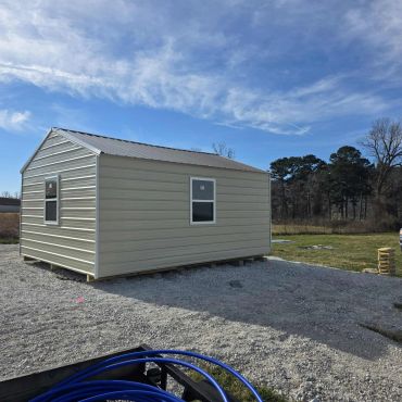 Small beige metal building under a partly cloudy sky.