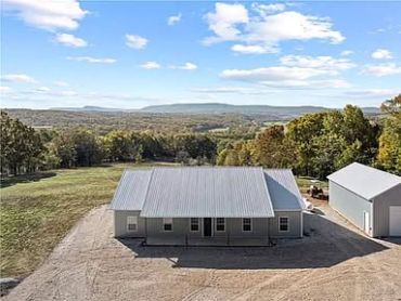 Single-story house with metal roof in a rural landscape.