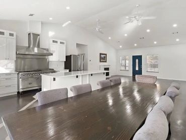 Modern open kitchen and dining area with white walls and high ceiling.