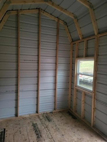 Interior of an unfinished small wooden shed with a window.