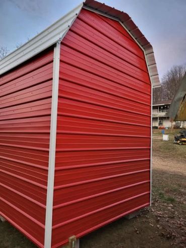 A red metal barn with white trim on a farm setting.